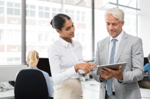 A fractional CFO helping the CEO on an ipad during a company meeting.