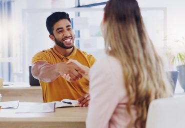 Man and women shaking hands at a table.