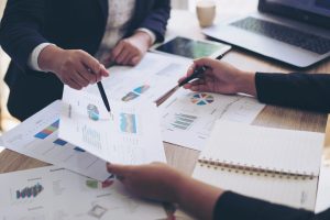 close up hand of marketing manager employee pointing at business document during discussion at meeting room , Notebook on wood table - Business concept
