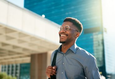 Business, happy and walking man on city journey, commute trip and real estate agent smile on way to office building. Happiness, career expert and real estate agent on morning travel