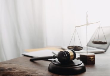 Business and lawyers discussing contract papers with brass scale on desk in office. Law, legal services, advice, justice and law concept picture with film grain effect