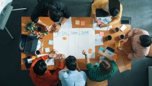 People sitting around a table planning on a white board with sticky notes
