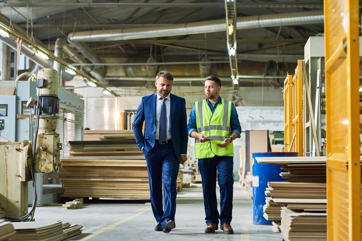 Full length portrait of young workman giving tour of modern factory to handsome mature businessman discussing possible investment, copy space