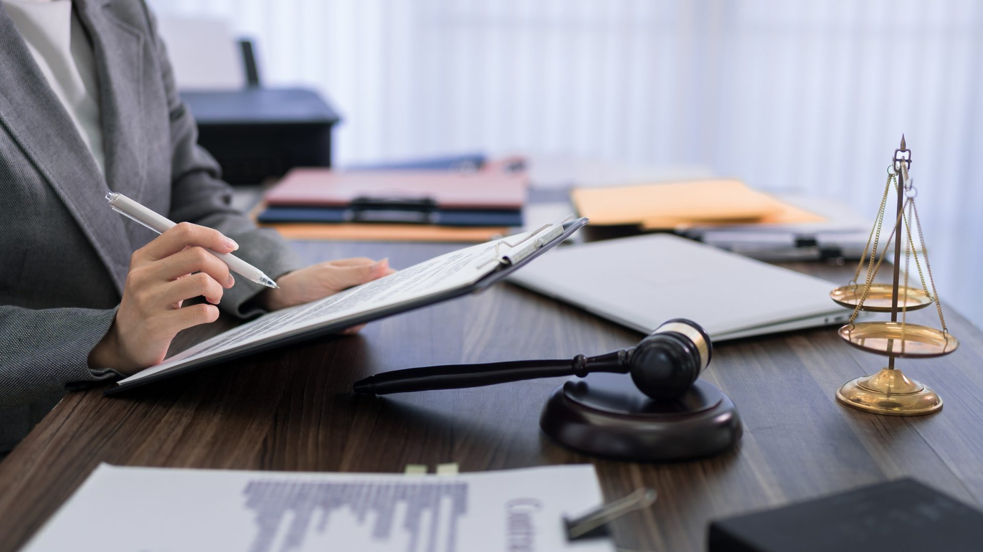 lawyer hand writing notes on legal documents at office desk with gavel scales of justice preparing case consultation