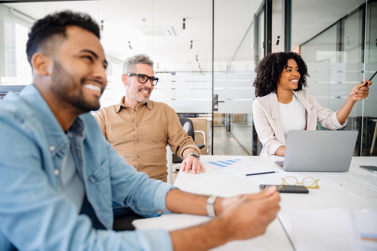 A team smiles broadly during a collaborative session. The image shows moment of genuine enjoyment and connectivity in modern corporate setting, highlighting positive dynamics of workplace interaction
